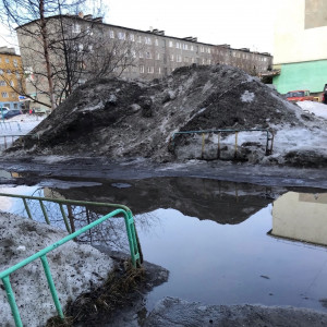 «Вода идет под дом»: северяне пожаловались на кучи тающего снега в мурманском дворе
